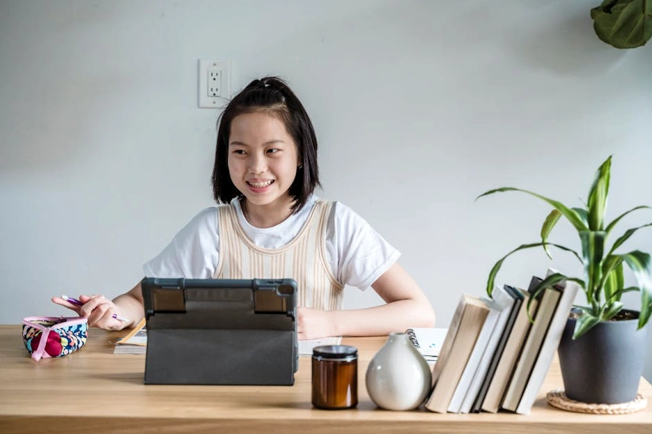 Osoba sedící u stolu a studující finanční grafy na tabletu.